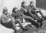 Four Jewish members of the Sixth Labor Battalion (VI Prapor) sit outside a building at a Slovak labor camp.
