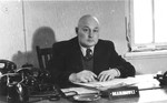 Portrait of Dr. Abrasha Blumowicz, a member of the executive of the Central Committee of Liberated Jews in the US Zone of Germany, seated at his desk.