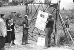 Workmen hang up a sign on the gate of the new IRO [International Refugee Organization] children's home in Leitendorf, Austria.