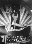 The emblem of the Surviving Remnant [Sheerit Hapletah] hangs above the dais at the Third Conference of Liberated Jews in the US Zone of Germany.