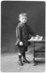 Studio portrait of a young German-Jewish child, Gerd Zwienicki, holding a picture book.