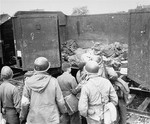 American soldiers of the U.S. 7th Army, force boys believed to be Hitler youth, to examine boxcars containing bodies of prisoners starved to death by the SS.