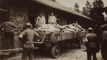 American soldiers look on as survivors in Dachau remove bodies from the cellar of the crematorium.