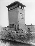 The bodies of SS guards, who were shot by American troops, lie on the edge of the moat at the base of a guard tower in Dachau.