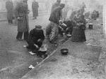 Survivors in Dachau prepare food for themselves during a spring snow shower.
