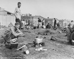 Survivors in Dachau cooking food over open fire.
