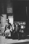 Two Jewish refugee children pose with a Chinese man on a street in Shanghai.