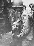 Philip Hannan, a chaplain with the 82nd Airborne Division, helps a prisoner into a truck that will transport him from the Woebbelin concentration camp to an American field hospital.