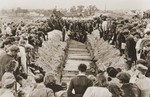 Mourners and local residents watch as pallbearers place the coffins of the victims of the Kielce pogrom in a mass grave at the Jewish cemetery.