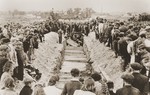 Mourners and local residents watch as pallbearers place the coffins of the victims of the Kielce pogrom in a mass grave at the Jewish cemetery.