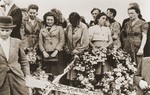 Mourners bearing wreaths and banners grieve at the funeral of the Kielce pogrom victims.