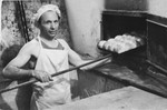 J. Weisblum removes a tray of breads from the oven at the Bindermichl displaced persons camp.
