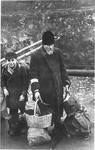 An elderly man and child who have been rounded-up for deportation wait with their luggage at an assembly point in the Krakow ghetto.