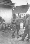 Japanese-American troops with the 522nd Field Artillery Battalion collect the belongings of three captured German Waffen-SS soldiers.