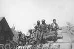 Japanese-American soldiers with the 522nd Field Artillery Battalion catch a ride on a tank destroyer near Dachau.