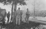 Survivors from a death march from Dachau huddle around a camp fire prepared by Japanese-American soldiers with the 522nd Field Artillery Battalion.