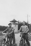 Two Jewish teenagers ride bicycles through Buchenwald prior to their leaving the camp for Switzerland.