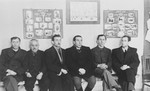 Edward Cittron and four other men sit in front of photo display in the ORT vocational school in Neu-Ulm.