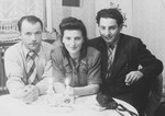 Three young Hungarian Jewish displaced persons sit around a table with lit candles.