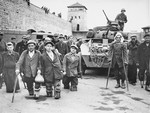 Disabled Polish and Russian survivors stand in front of a tank from the 11th Armored Division, Third U.S.