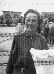 Portrait of a female survivor of Mauthausen standing behind the barbed wire fence.