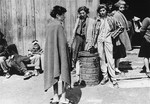 In the women's camp at Mauthausen, survivors stand around the entrance to a barracks.