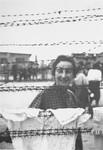 Etta Krevstlen, a survivor in Mauthausen, poses behind a barbed wire fence.