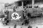 American soldiers pose with a captured Nazi flag after liberating the Mauthausen concentration camp.