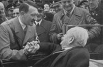 Amid a crowd of people, Adolf Hitler congratulates Karl-Siegmund Lizmann on his birthday.