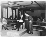 Defendant Dr. Klaus Schilling examines evidence on the stand in the Dachau trial.