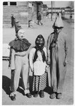 Three children in the Wels DP camp pose outside in their Purim costumes.
