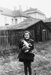 Kitty Weichherz stands by a fence holding a cat [perhaps in Cadca].