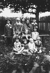 An elderly Jewish couple poses in a garden surrounded by their grandchildren.