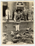 A young girl feeds pigeons in an public square in Warsaw.