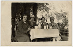 Four sisters enjoy a cup of coffee at an outdoor table.