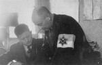 Leon Rozenblat, chief of the Lodz ghetto police (right) works with  Hermann Chimowicz in his office.