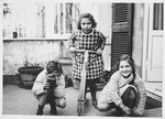 Three Jewish children play in the courtyard of their home.