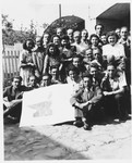 Group portrait of Jewish DPs who are members of the Dror-Hehalutz Zionist youth movement, posing with a sign in Litomerice, Czechoslovakia.