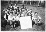 Group portrait of Jewish DPs of the Dror Hehalutz Zionist youth movement posing with a sign while on an outing in Czechoslovakia.