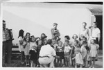 A man with an accordian accompanies a group of young children in song in the Ferramonti internment camp.