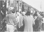 Jewish displaced persons board and exit a train in a busy station in Germany.