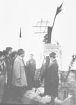 Jewish survivors stand at the memorial of Aharon Dolek Liebeskind.