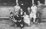 An extended Jewish family from Vilna poses outside a wooden cottage while on vacation in Podbrodzie.
