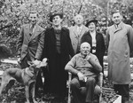 A German-Jewish family poses outdoors for a family portrait with their dog.
