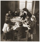 Children at the OSE children's home, Château de Vaucelles, in Taverny, sit around a table with their English teacher.