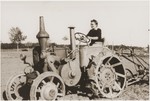 An American woman drives a tractor at the Kibbutz Nili hachshara (Zionist collective) in Pleikershof, Germany, where she came to get agricultural training.