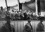 Adolf Hitler stands on a podium in the Luitpold Hall in Nuremberg with Rudolf Hess, Heinrich Himmler, and Joseph Goebbels during Reichsparteitag (Reich Party Day) ceremonies.