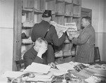 Gestapo officers and a member of the Schutzpolizei look through newspapers and publications during the closing of the Karl-Liebknecht House (KPD headquarters) on the Buelowplatz in Berlin.