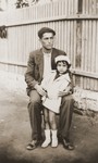 Portrait of a young man holding a little girl in front of a fence.