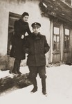 A Jewish policeman poses with a young woman on a snow covered street in the Biala Rawska ghetto.